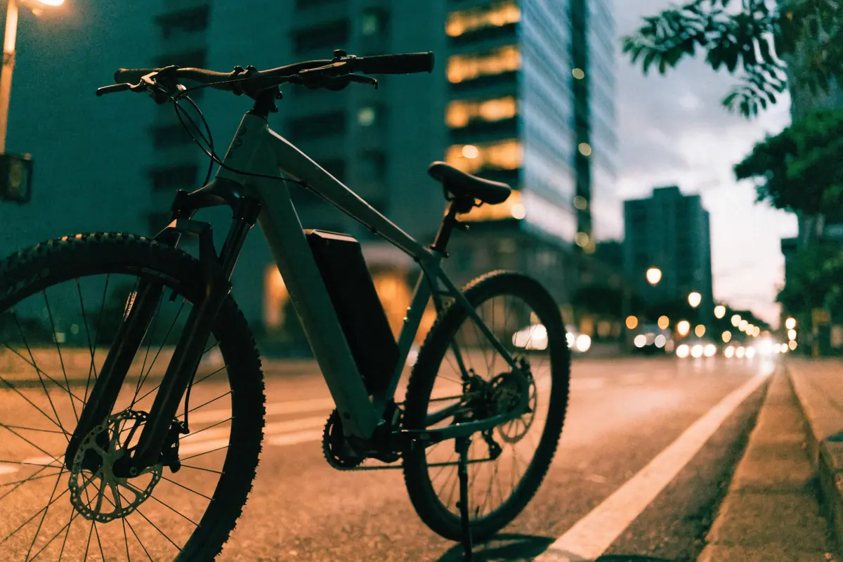 Bicicleta elétrica com bateria no quadro parada na ciclovia de uma avenida ao anoitecer